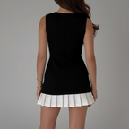 Back view of black top with white pleated skirt